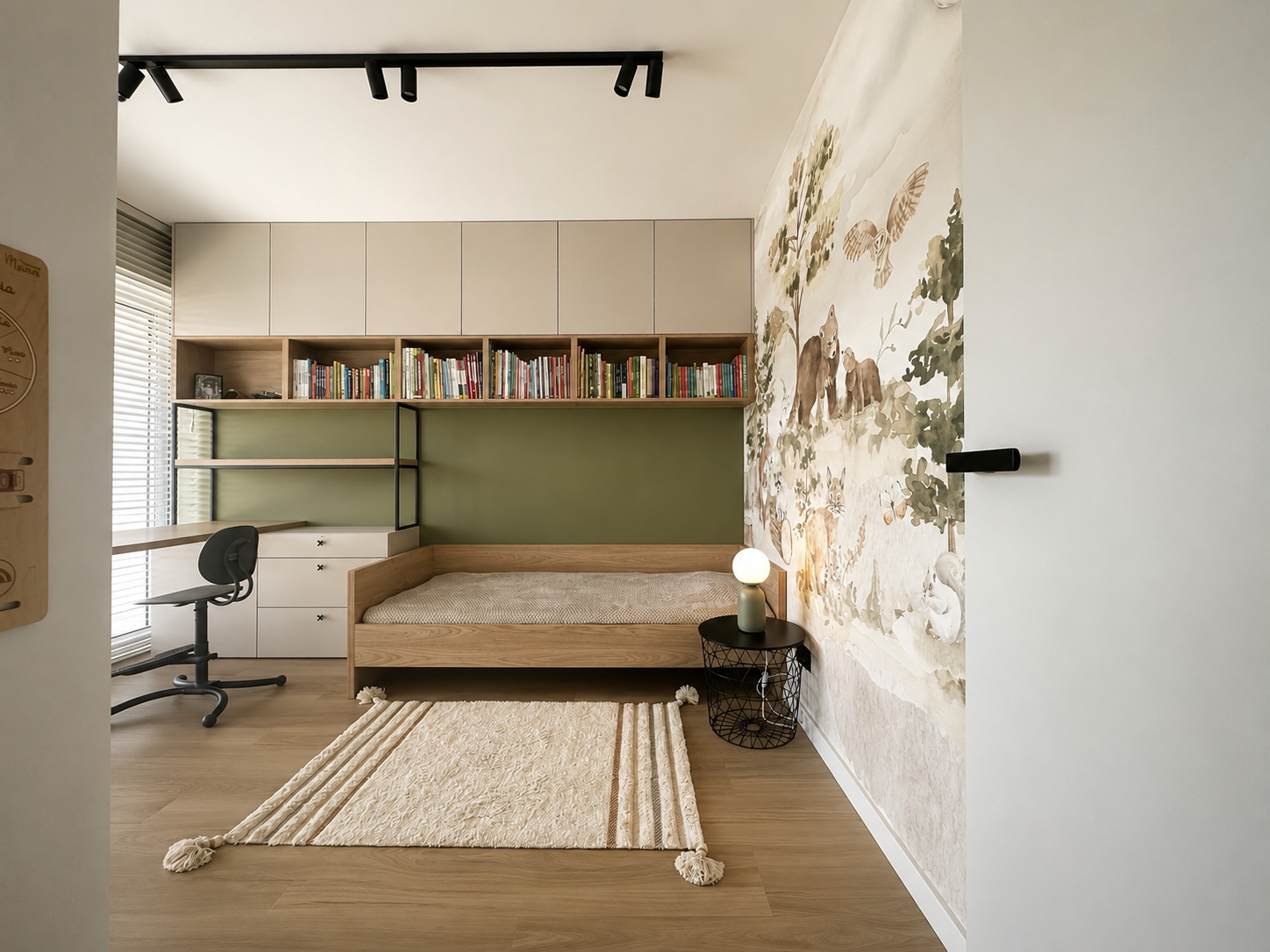 Funkcjonalny pokój dziecka z zielonym akcentem, miejscem do nauki i leśną tapetą.